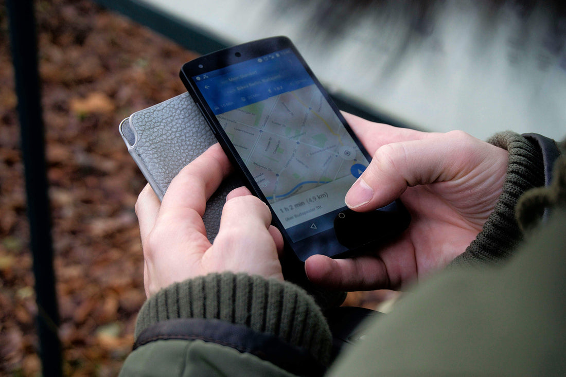 Persona usando un teléfono para buscar un localizador de objetos en un mapa.