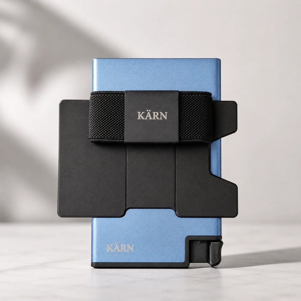 Tarjetero RFID KÄRN de aluminio azul con tarjeta visible, banda elástica negra y diseño slim para uso diario.