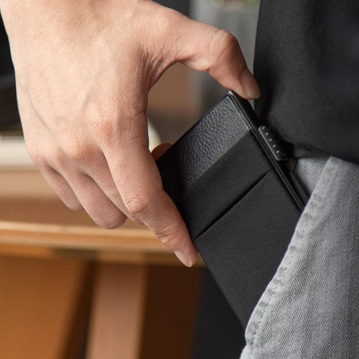 Persona sacando el tarjetero RFID Slim Access KÄRN de su bolsillo con tarjeta localizadora Bluetooth.